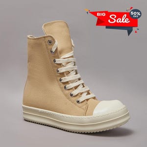 May include: Tan high-top sneaker with a white toe cap and sole. The canvas shoe has white laces and metal eyelets. A red banner with the text "BIG Sale" and "50% OFF" is in the upper right corner.