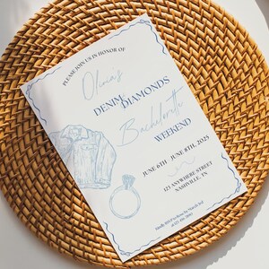 May include: A white invitation card with blue text and illustrations. The text reads "Please join us in honor of Olivia's Denim Diamonds Bachelorette Weekend June 6th June 8th, 2025 123 Anywhere Street Nashville, TN"