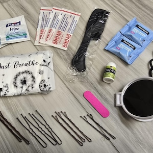 May include: An assortment of personal care items, including Purell wipes, Band-Aids, a comb, makeup remover wipes, hair ties, bobby pins, a nail file, Chap-Ice lip balm, and a compact mirror. A tissue pack with the words "Just Breathe" is also included.
