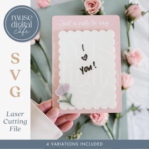 May include: A pink card with a scalloped edge and the text "Just a note to say..." and "I love you!" written in black marker. The card has a small pink flower design in the bottom left corner.