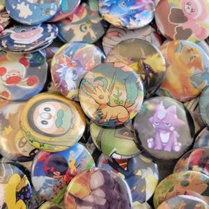 Può includere: Una collezione di bottoni colorati con personaggi di Pokemon. I bottoni presentano vari personaggi di Pokemon, tra cui Pikachu, Eevee e Charizard. I bottoni sono in plastica e hanno una finitura lucida.