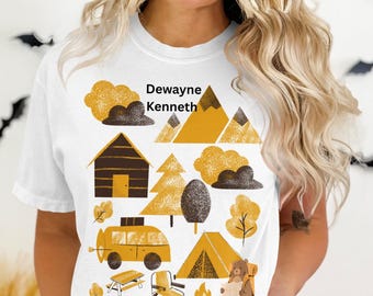 Puede incluir: Camiseta blanca con un diseño de temática de camping. El diseño incluye una cabaña, montañas, árboles, una furgoneta camper, una tienda de campaña y un oso con una mochila. El nombre "Dewayne Kenneth" está impreso en la parte superior.