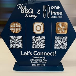 May include: A blue and white hexagonal sign with the text "The BBQ King & one three Catering & Events". The sign has three QR codes, a globe icon, an Instagram icon, and a Yelp icon. The sign also has the text "Let's Connect!" and contact information for The BBQ King.