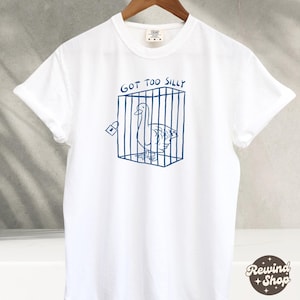 May include: White t-shirt with a blue graphic of a goose in a cage. The text "GOT TOO SILLY" is above the graphic.
