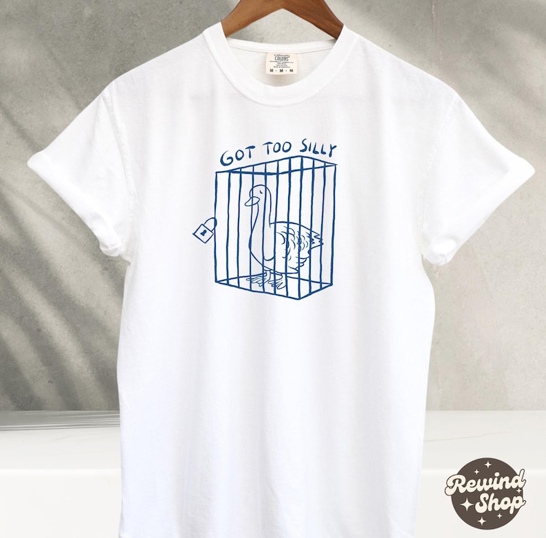 May include: White t-shirt with a blue graphic of a goose in a cage. The text "GOT TOO SILLY" is above the graphic.