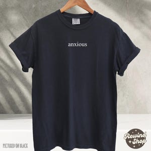 May include: A black t-shirt with the word "anxious" printed in white on the front.