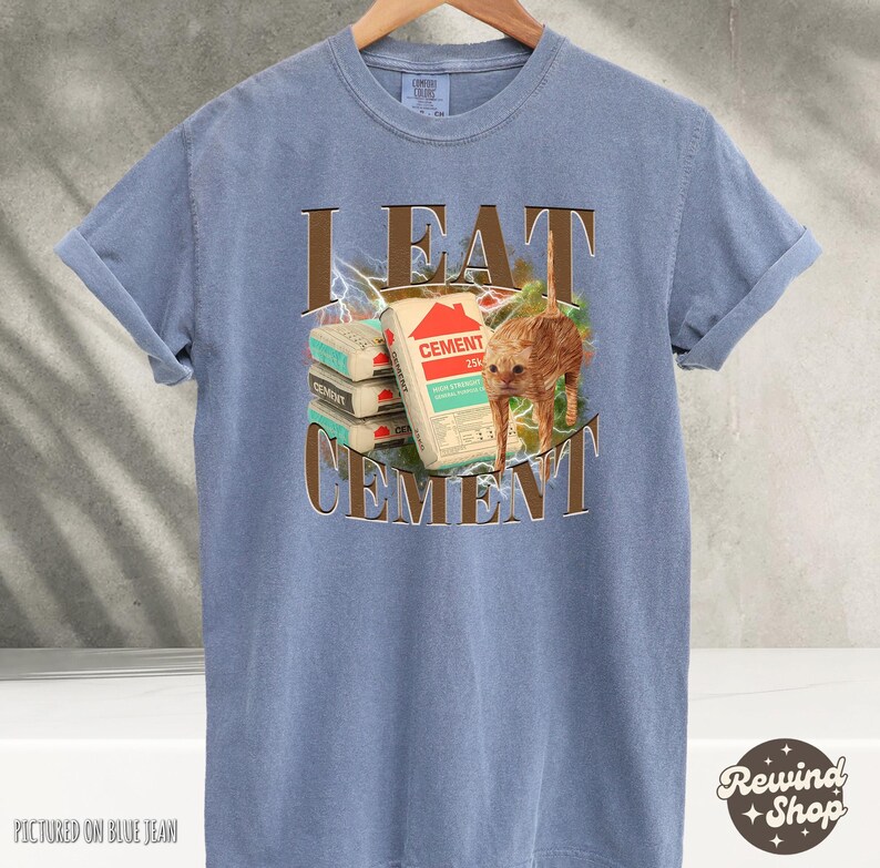 May include: A blue t-shirt with the text "I EAT CEMENT" in brown letters. A cartoon cat is eating a stack of cement bags.