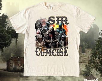 Puede incluir: Camiseta color crema con un gráfico de caballeros con armadura y el texto "SIR CUMCISE". El diseño tiene un tema medieval con un fondo de castillo.