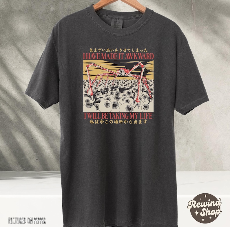 May include: Dark gray t-shirt featuring a graphic with a red and yellow spider-like creature above a field of white eyeballs. The text "I HAVE MADE IT AWKWARD" and "I WILL BE TAKING MY LIFE" are also displayed.