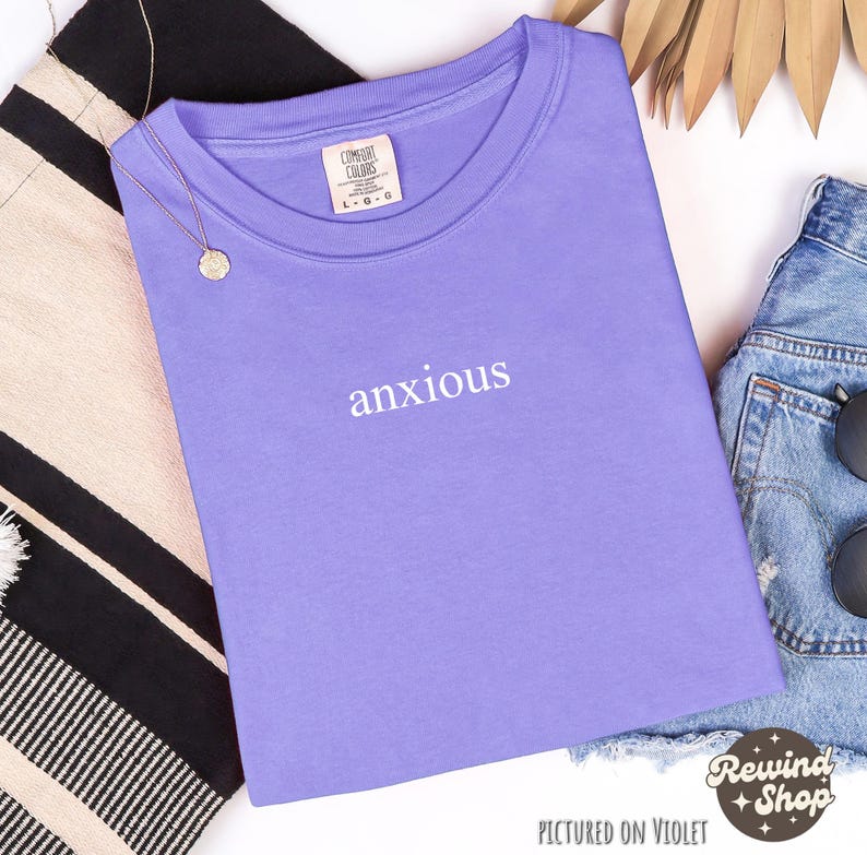 May include: A purple t-shirt with the word "anxious" printed in white on the front.