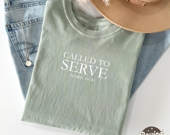 Può includere: Una maglietta verde salvia con il testo "Called to Serve" e "Mark 10:45" in lettere bianche.