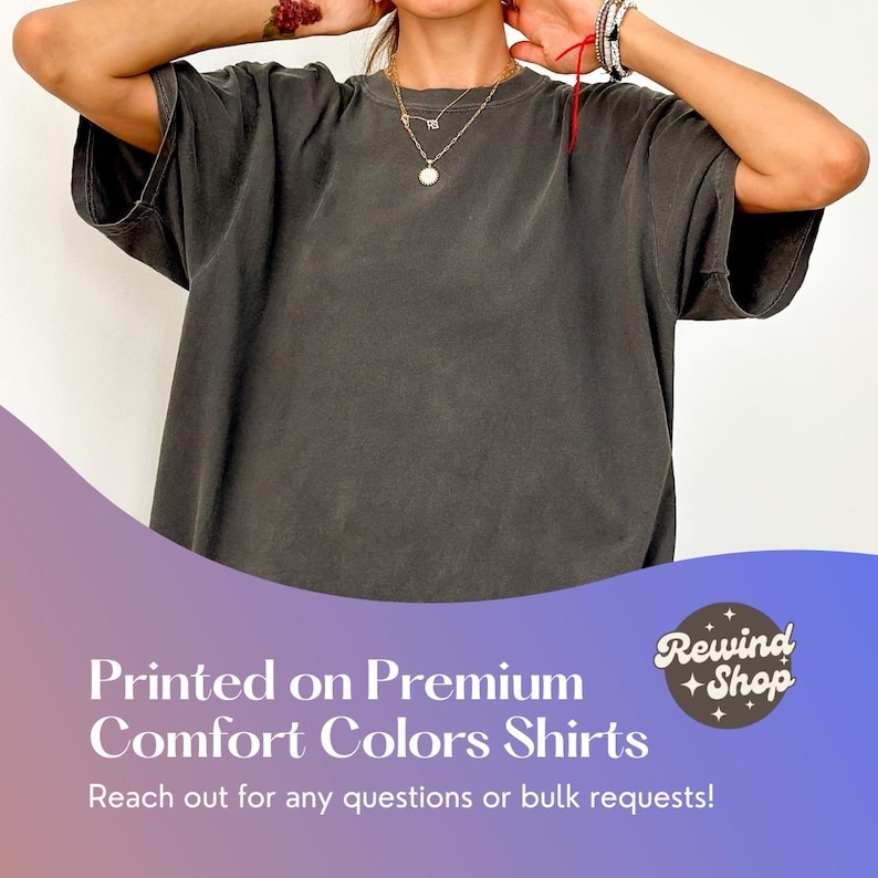 May include: A charcoal gray oversized t-shirt with a crew neck. The t-shirt is made of a soft, comfortable fabric. "Rewind Shop" is printed in a circle on the bottom right corner of the image.