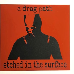 Puede incluir: Un gráfico cuadrado rojo con una silueta negra de la parte superior del cuerpo de una persona. El texto "a drag path" está en la parte superior y "etched in the surface" en la inferior. La imagen tiene un estilo minimalista y artístico.