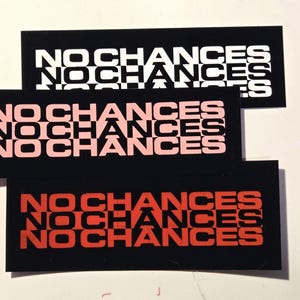 Puede incluir: Tres pegatinas rectangulares con las palabras «NO CHANCES» apiladas tres veces. La pegatina superior tiene texto blanco sobre fondo negro. La pegatina del medio tiene texto rosa sobre fondo negro. La pegatina inferior tiene texto rojo sobre fondo negro.