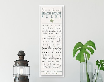 May include: A white sign with black text that reads "Sass & Jenny's Beach House Rules" with a green starfish graphic. The rules include "Don't be Crabby", "Go Barefoot", "Make Memories", "Collect Seashells", "Enjoy the Fresh Air", "No Worries", "Swim Like a Fish", "Laugh a Lot", "Breathe Deeply", "Take a Nap", "Relax & Play", "Toey in the Sand", "Make Sandcastles", "Take a Long Walk", "Watch the Sunset", "Clearwater, Florida Est. 2011".