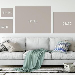 a living room with a couch and samples of different print sizes on the wall
