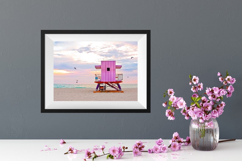 a desk with a photo of a pink lifeguard stand on miami beach at sunrise above it. photography by catch a star fine art.