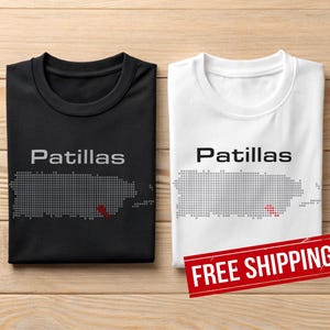 Könnte beinhalten: Zwei T-Shirts, eines schwarz und eines weiß, jeweils mit dem Wort "Patillas" über einer gepunkteten Umrisslinie von Puerto Rico. Das schwarze Shirt hat eine graue Umrisslinie, und das weiße Shirt hat eine graue Umrisslinie. Ein rotes "FREE SHIPPING" Banner ist sichtbar.
