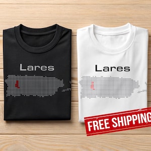 May include: Two t-shirts, one black and one white, featuring the word "Lares" above a dotted map of Puerto Rico. The map includes a red dot. The shirts are displayed on a wooden surface.