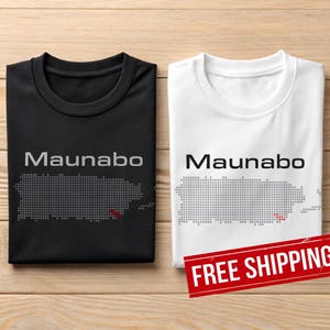 May include: Two t-shirts, one black and one white, each displaying the word "Maunabo" above a dotted outline of Puerto Rico. The black shirt has a grey design, while the white shirt has a grey design with a red accent.