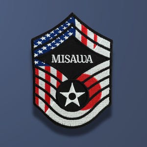 May include: A black and white patch with the text "MISAWWA" in white. The patch features the American and Japanese flags, with a white star in the center.