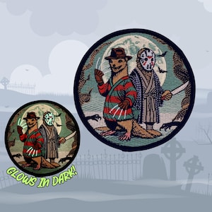 Może przedstawiać: Dwa haftowane naszywki przedstawiające dwa fretki ubrane w postaci postaci z filmów grozy. Większa naszywka przedstawia fretki ubrane jako Freddy Krueger i Jason Voorhees. Mniejsza naszywka to ten sam obraz, ale świeci w ciemności. "Glows in Dark!" jest napisane pod mniejszą naszywką.