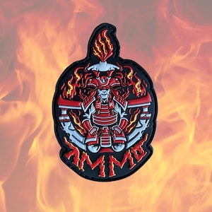 May include: A black and red embroidered patch with a samurai warrior in a red and white suit of armor. The warrior is surrounded by flames and the word "AMME" is written in a stylized font around the outside of the patch.