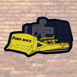 May include: A yellow and black bulldozer patch with the words "PUSH BACK" printed on the blade.