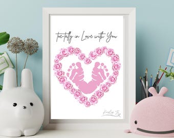 May include: A white framed print with a pink heart made of paper roses. Inside the heart are two pink baby footprints. The text "toe-tally in love with you" is above the heart. The signature "Kindly Fox" is below the heart.