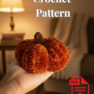May include: A plush, orange crochet pumpkin with a brown stem. The image includes the text "Crochet Pattern" in white, and a red PDF icon with a downward arrow, suggesting a downloadable pattern.