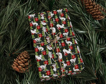 May include: Wrapped gift with a festive Christmas-themed wrapping paper. The paper features a repeating pattern of white dogs, green Christmas trees, and red gift boxes on a dark green background. The gift is tied with twine and set on a bed of pine needles and pine cones.