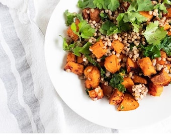 Puede incluir: Un plato blanco lleno de una colorida comida a base de plantas. El plato presenta cubos de batata asada, granos y cilantro verde fresco. El texto "Plant-Based Low FODMAP Diet" es visible.