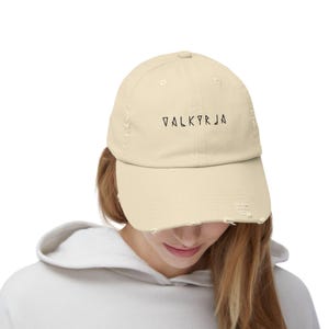 May include: A light beige distressed baseball cap with black embroidered text that reads "VALKYRJA".
