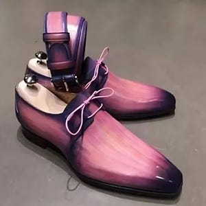 May include: A pair of pink leather shoes with a purple ombre effect. The shoes have a lace-up design with pink laces and a matching pink belt.