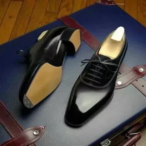 May include: A pair of black leather dress shoes with lace-up fastenings. The shoes have a pointed toe and a polished finish.