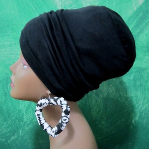 May include: A black fabric turban with a heart-shaped earring with a black and white pattern.
