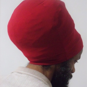 May include: A red, close-fitting, stretchy fabric hat. The hat is worn on a person's head.