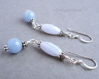 May include: A pair of silver dangle earrings with light blue gemstone beads. The earrings feature a round bead and an oval bead on each earring.