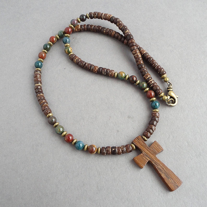 May include: A brown wooden cross pendant necklace with brown, red, and blue beads.