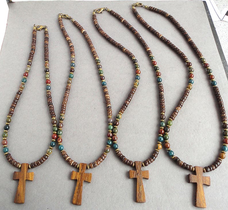 May include: Four wooden cross necklaces with brown, green, and red beads. The crosses are made of dark wood and have a simple design.