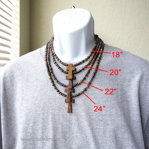 May include: A multi-strand necklace with wooden beads and cross pendants. The necklace is shown on a model and is available in four lengths: 18 inches, 20 inches, 22 inches, and 24 inches.