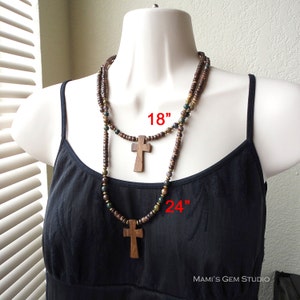 May include: Two wooden bead necklaces with cross pendants. The shorter necklace is 18 inches long and the longer necklace is 24 inches long.