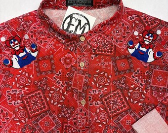 May include: Red button-up shirt with a bandana pattern and clown patches. The shirt has a gradient design and wooden buttons. The label reads "Ellie Monster Nashville" with an "EM" logo.