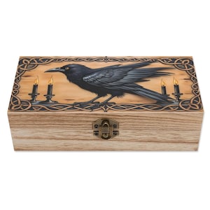 May include: Wooden box with a raven illustration. The raven is black with detailed feathering, perched on a branch with three lit candles. The box has a decorative border and a metal clasp.
