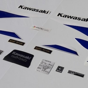 May include: A set of adhesive decals for a Kawasaki AR50S Special motorcycle, featuring blue and white graphic stripes, Kawasaki logos, AR50S Special text, uni-trak labels, and various small black and white technical warning stickers on a white background.