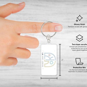 May include: A rectangular keychain with a glossy finish, featuring the text "LK ART IDEAS" and a graphic design. The keychain is 1 inch wide and 2 inches tall. It has a two-layer acrylic design and a protective film.