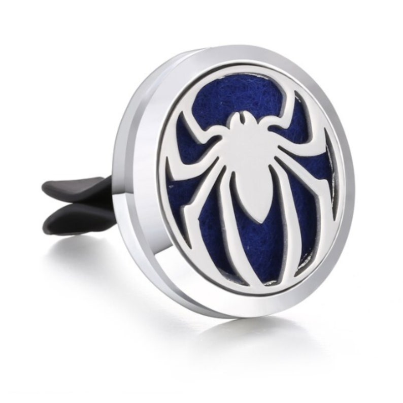 May include: Silver car air freshener with a spider design. The air freshener has a blue felt pad inside.