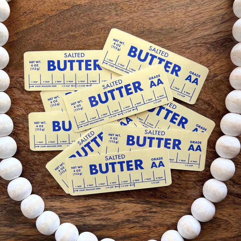 May include: A collection of rectangular, yellow butter measure cards with blue text. Each card reads "SALTED BUTTER" and includes measurement markings for tablespoons and cups. The cards are labeled "NET WT. 4 OZ (113g)" and "GRADE AA".