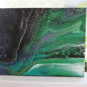 Könnte beinhalten: Abstrakte Acrylmalerei auf Leinwand. Das Kunstwerk zeigt ein fließendes Design mit Schattierungen von Schwarz, Grün, Türkis und Lila. Die Farben verschmelzen und wirbeln und erzeugen einen dynamischen und strukturierten visuellen Effekt. Die Leinwand ist rechteckig.