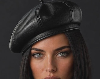 May include: A black beret with a textured finish and a small central stem detail. The beret features stitched paneling across the crown and a structured band. The text "Small Space COLLECTIONS" is printed in gold lettering at the bottom.
